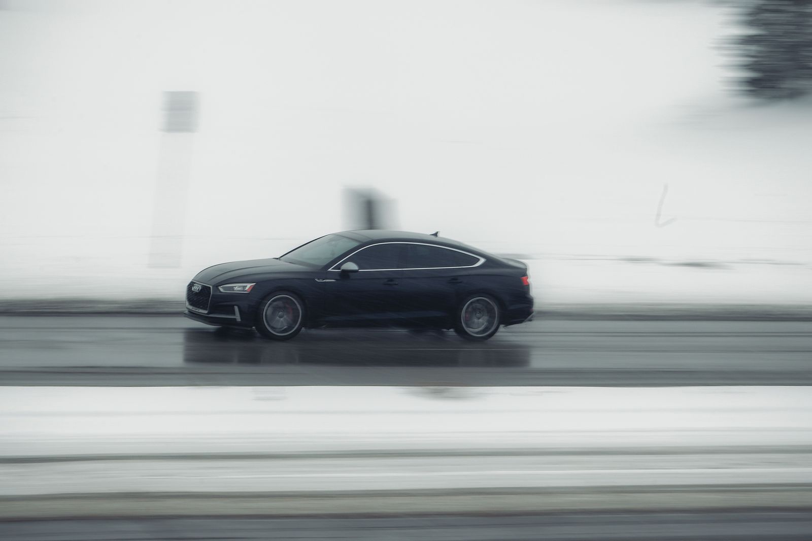 A black sedan on a winter highway, typical of the Montreal to Toronto run on the 401