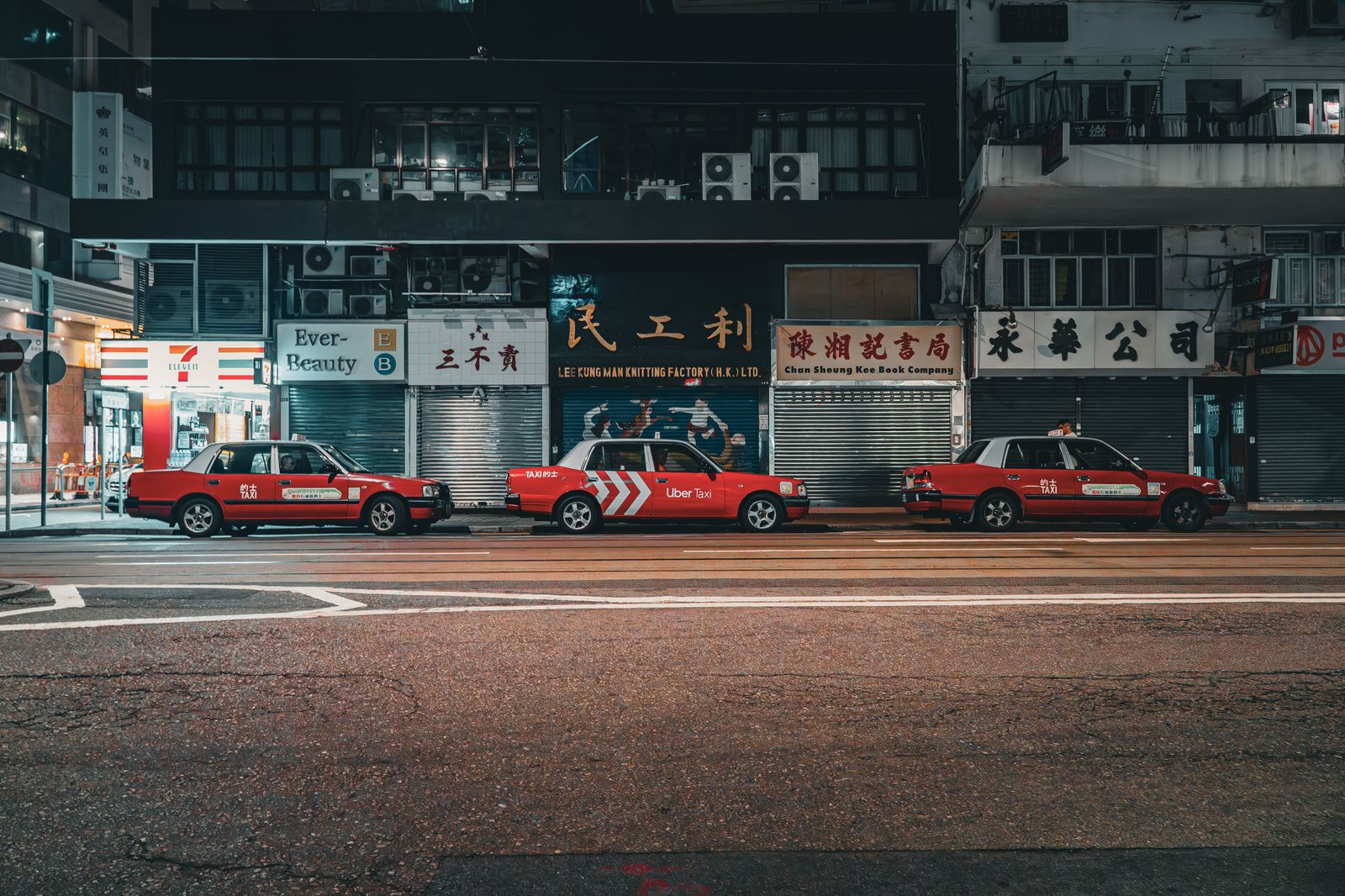 A line of travellers waiting for cars outside an airport arrivals level at night