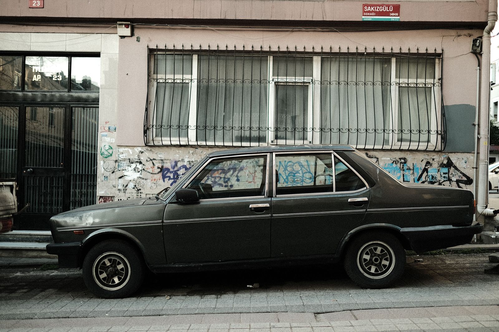 A black sedan parked on a city street, ready for a pre-booked airport run