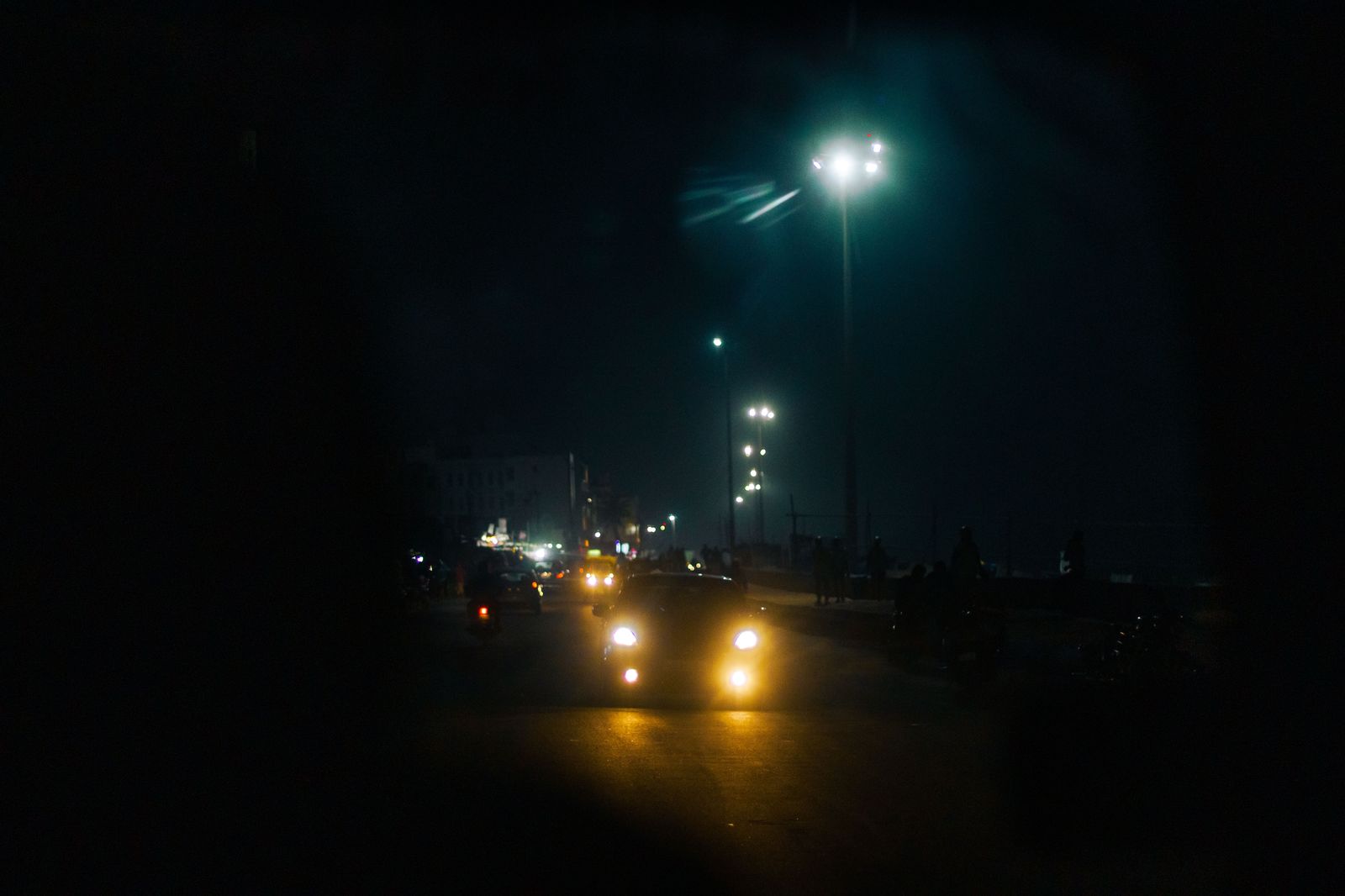 Car headlights on a dark residential street before dawn