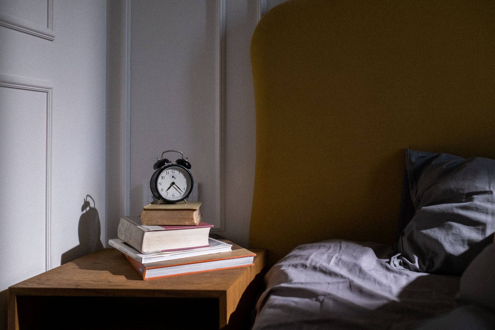A bedside alarm clock glowing in a dark room before an early flight