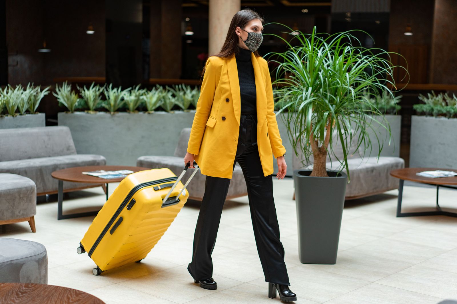 A traveller with a suitcase in a quiet airport hotel lobby at night