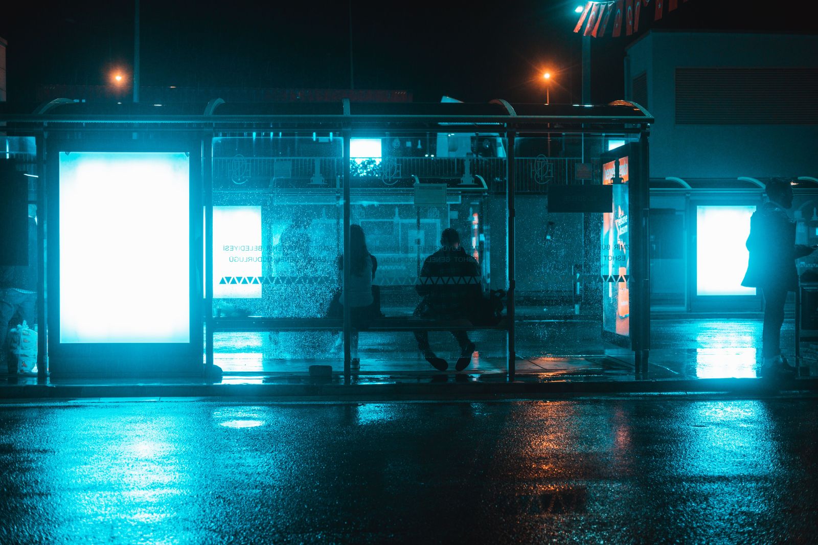 A city bus stop lit up at night, the overnight transit option from the airport