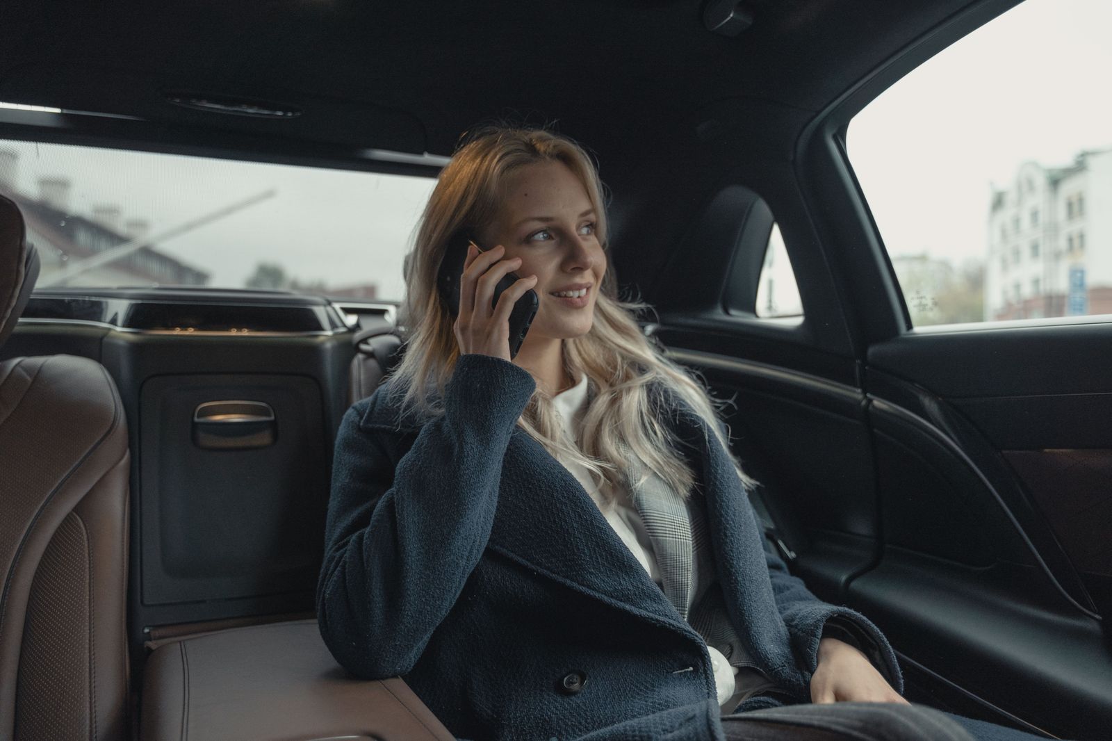 A business traveller working in the back seat of a chauffeured car