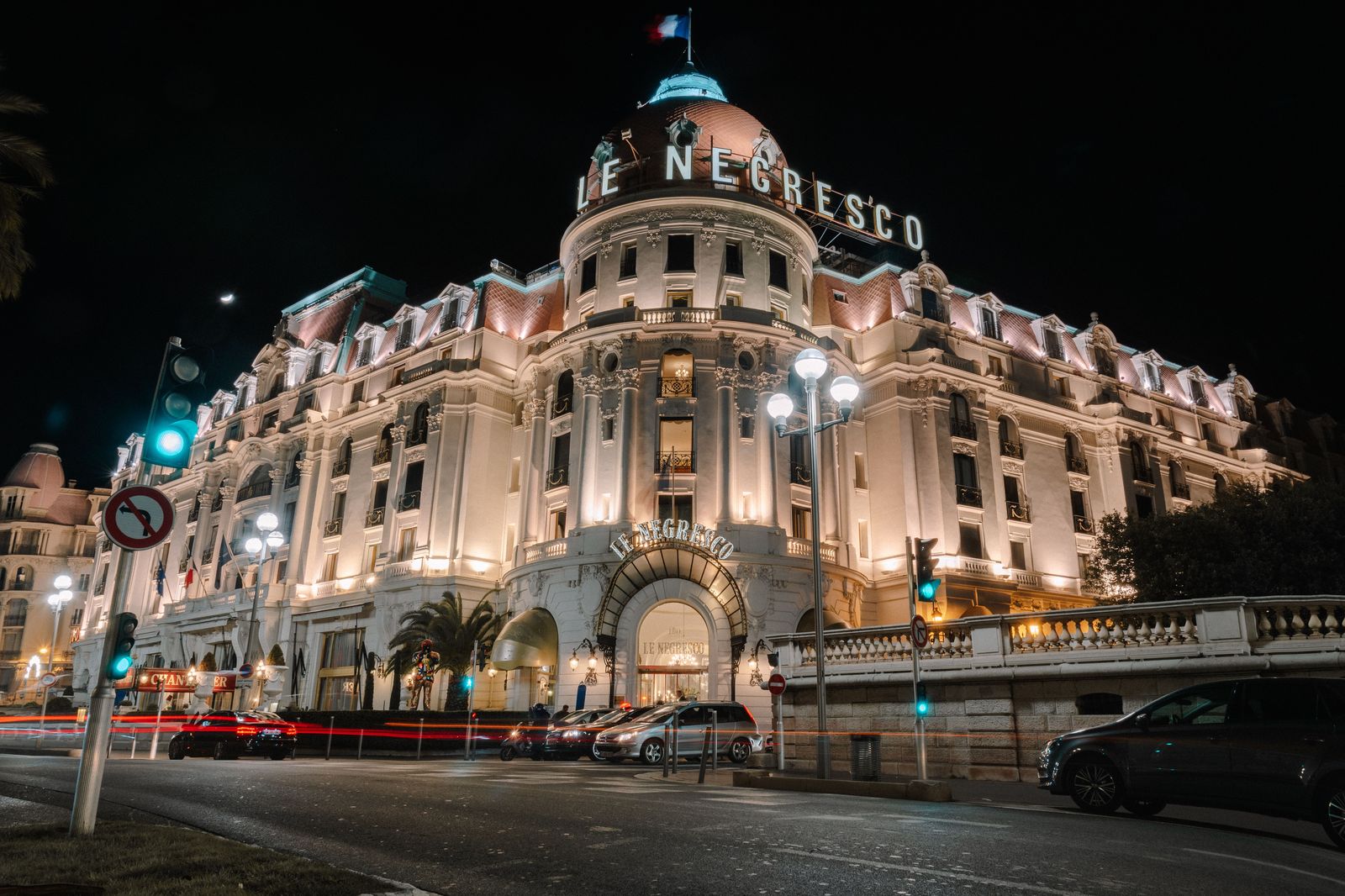 A chauffeured car waiting at a hotel entrance at night
