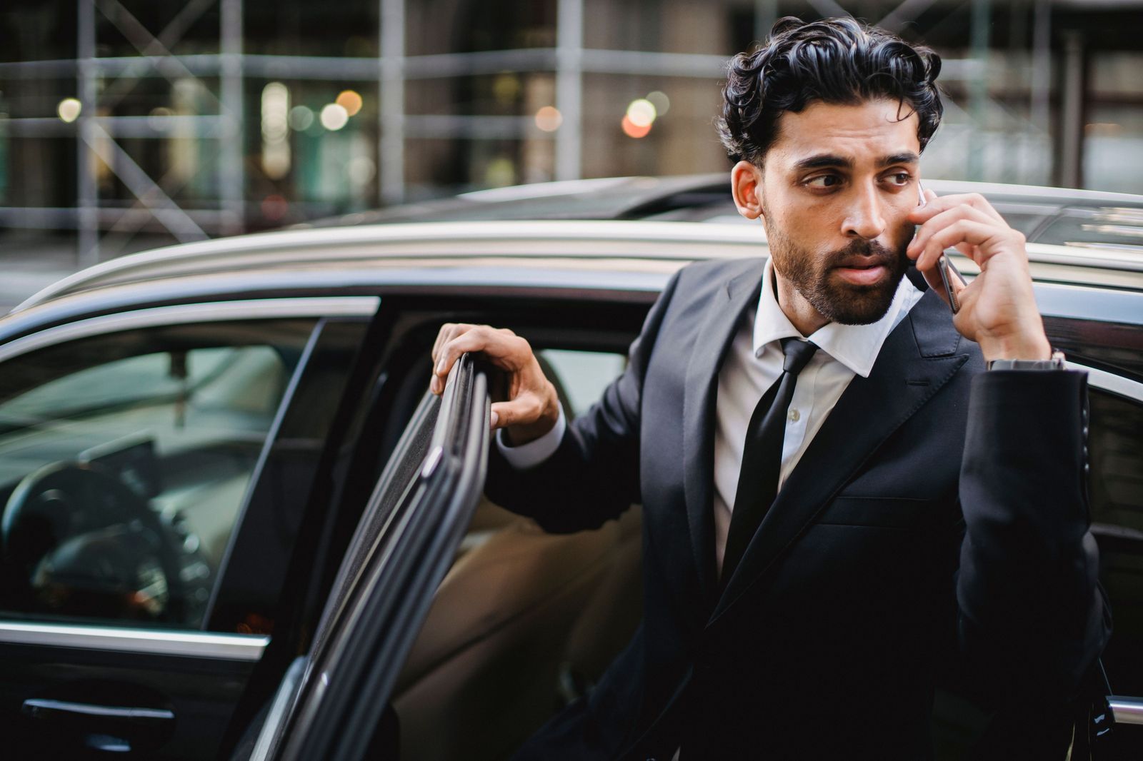 A business traveller on a phone call in the back seat of a chauffeured car heading to the airport