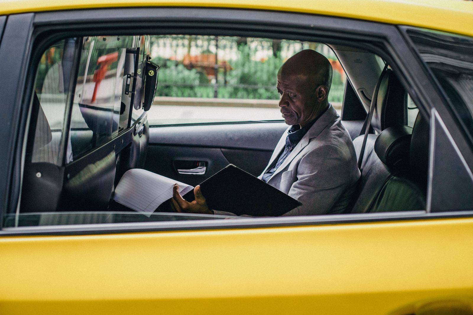 An executive working on a laptop in the rear seat of a chauffeured car on the highway