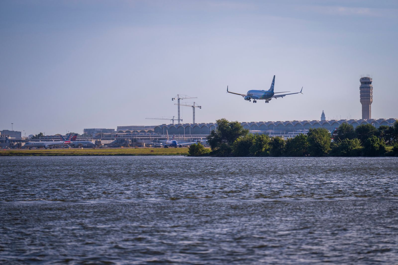 An aircraft on a lakeside runway with a city skyline behind