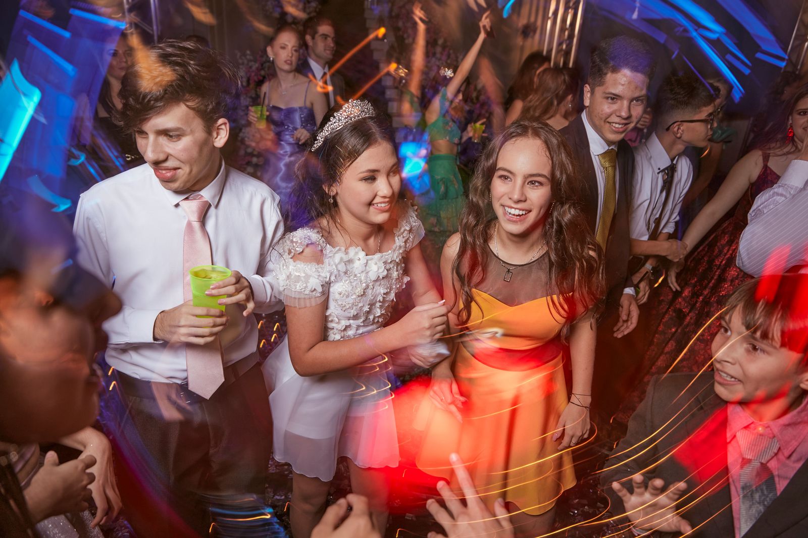 Graduates in formal wear beside a stretch limousine on prom night