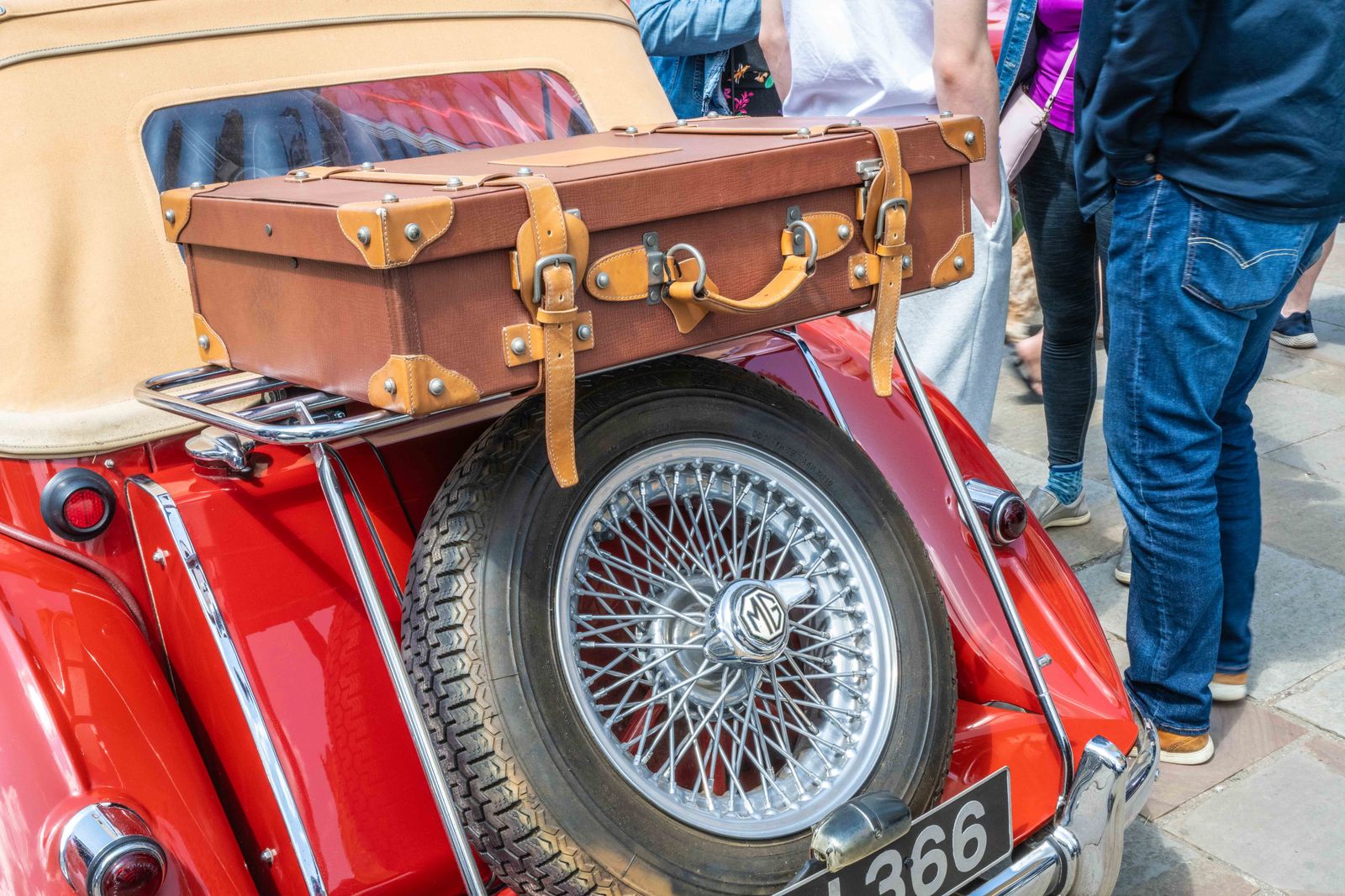 A family loading suitcases into the back of a car outside an airport