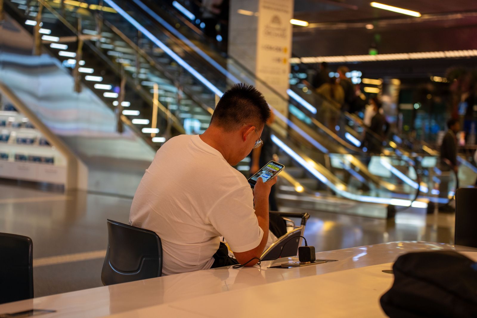 A traveller checking a phone while waiting outside an airport terminal