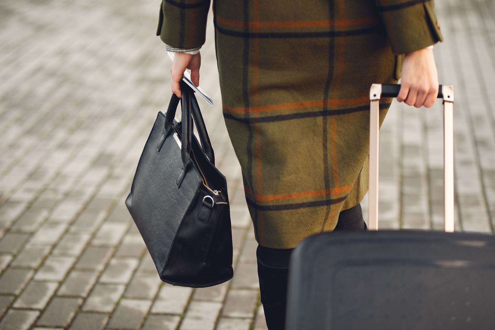 A traveller rolling a suitcase along a busy downtown sidewalk