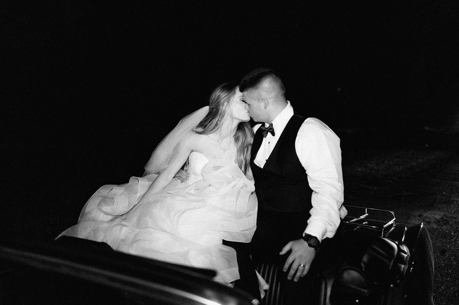 A wedding couple beside a white limousine on their wedding day