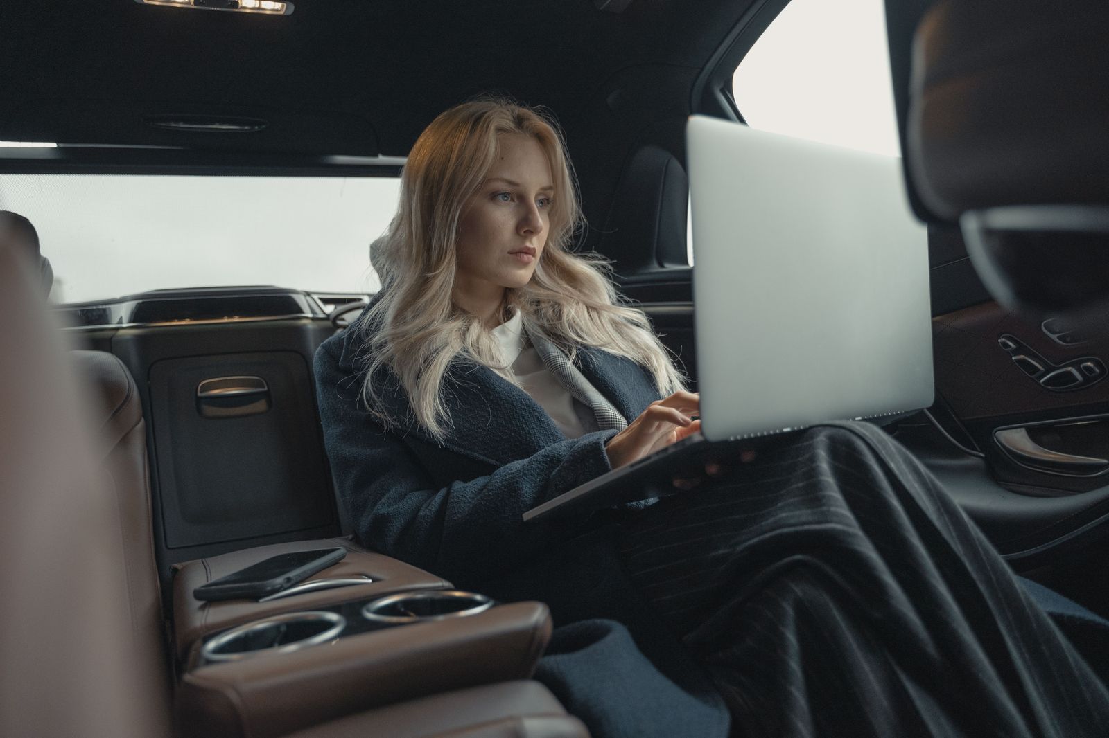 A business traveller working on a laptop in the back seat on the 401 between Pearson and Kitchener-Waterloo