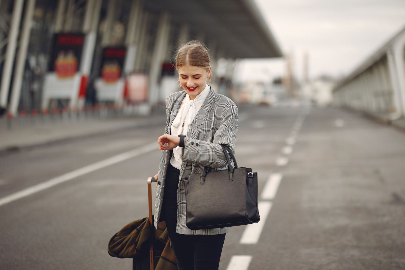 A business traveller with a carry-on case stepping to the curb for a pre-booked car at the airport
