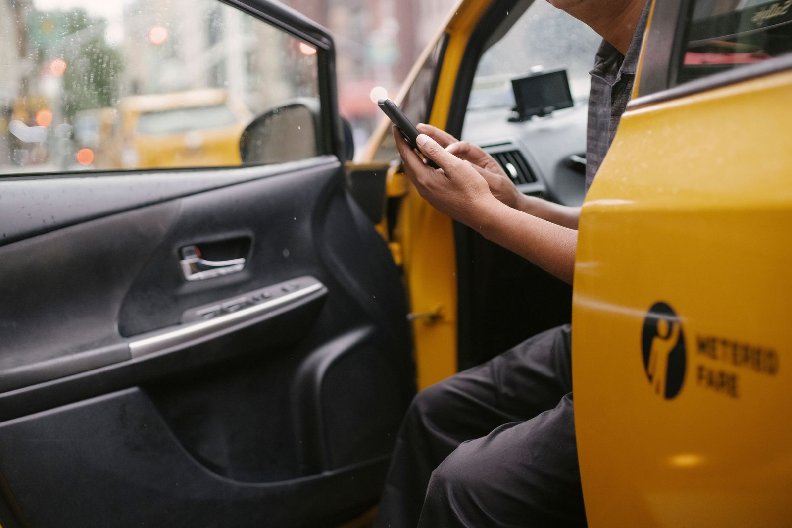 A chauffeur holding the rear door of a black car for a traveller returning home from Pearson