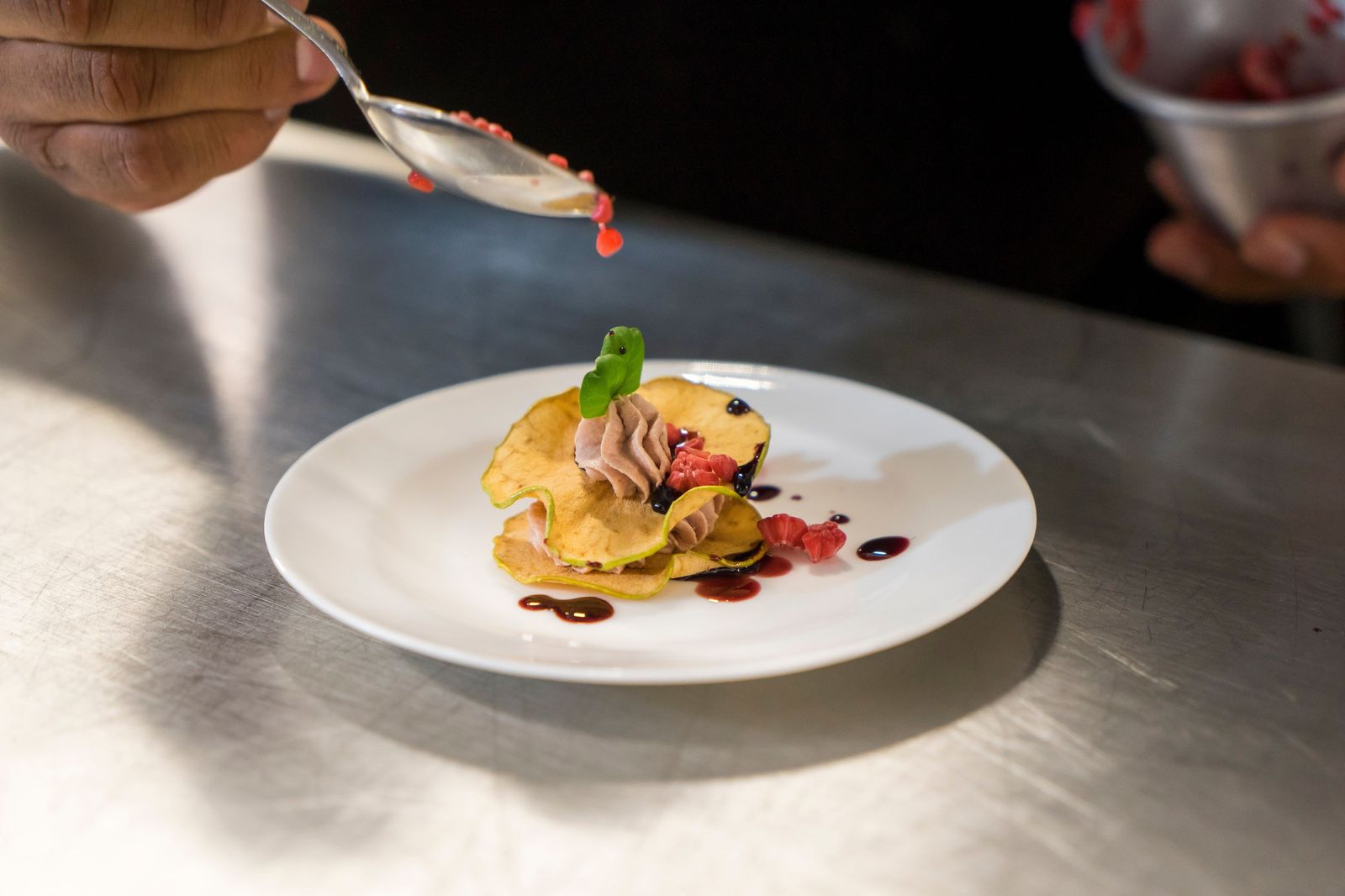 A plated dessert on the pass of a restaurant kitchen