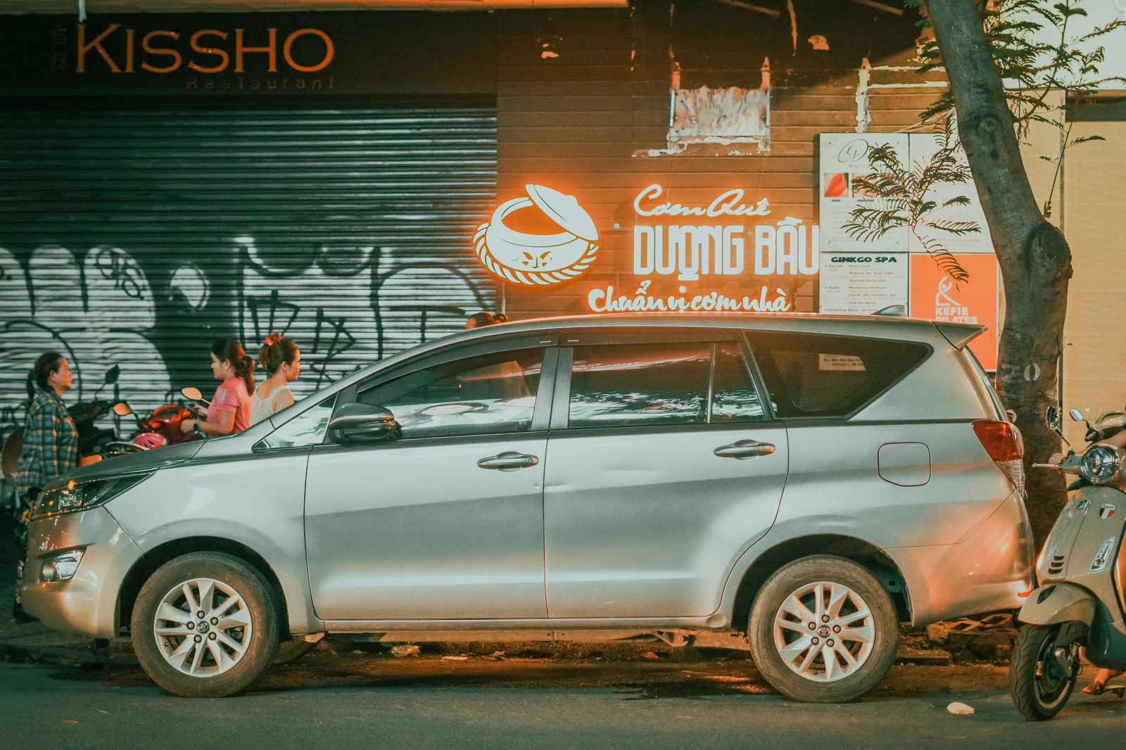 A couple stepping out of a car in front of a restaurant in the evening