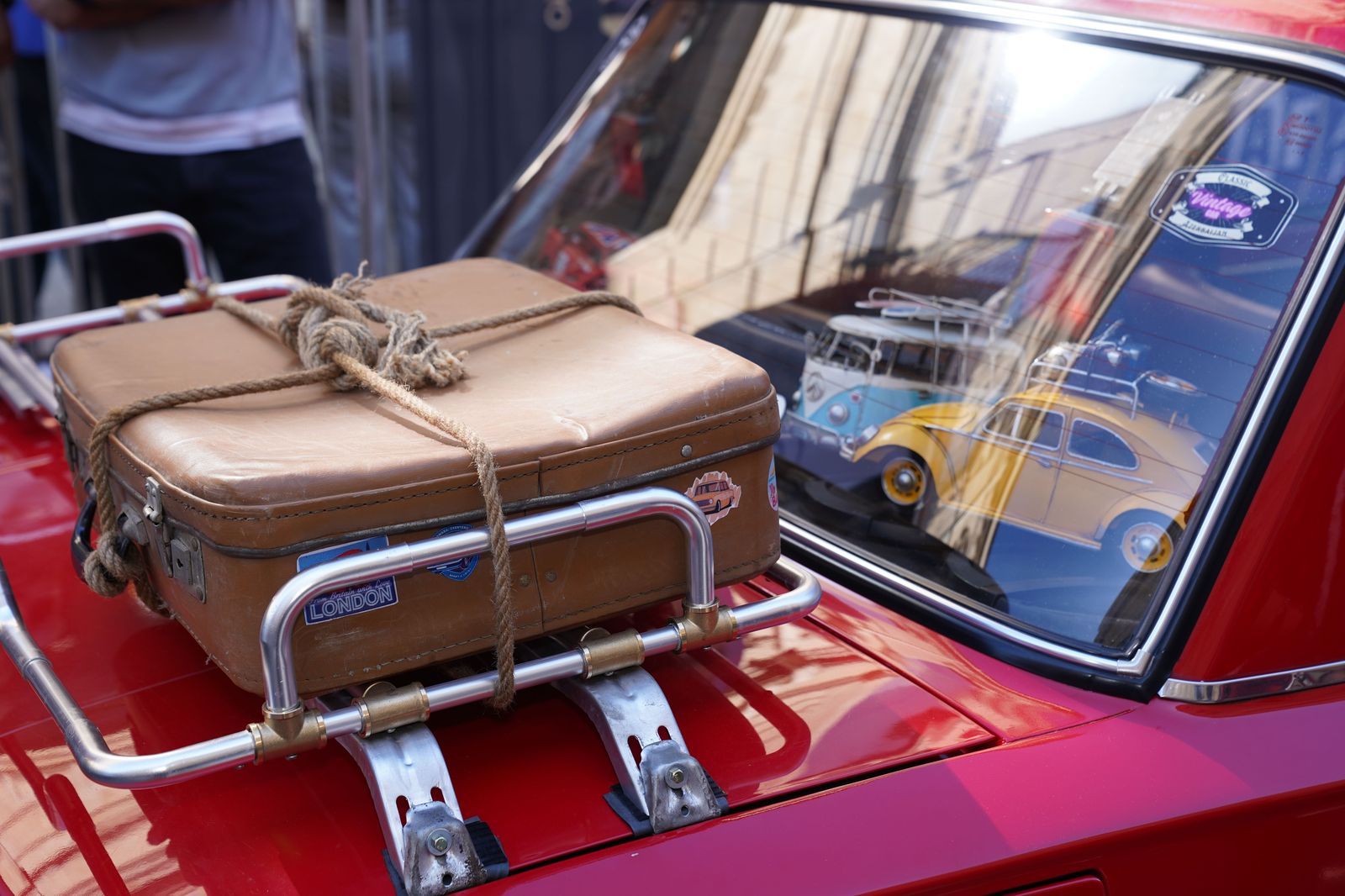 Luggage being loaded into the boot of a black car beside a hangar
