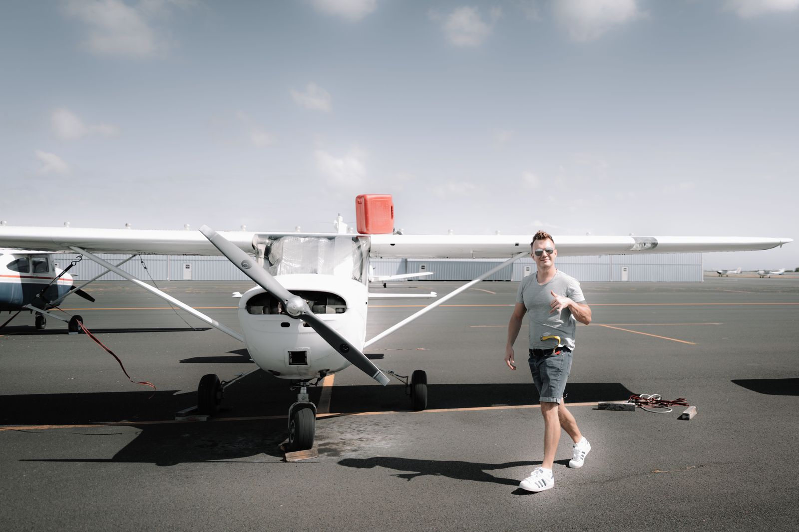 A pilot walking across the apron toward a light business aircraft at a general aviation airport