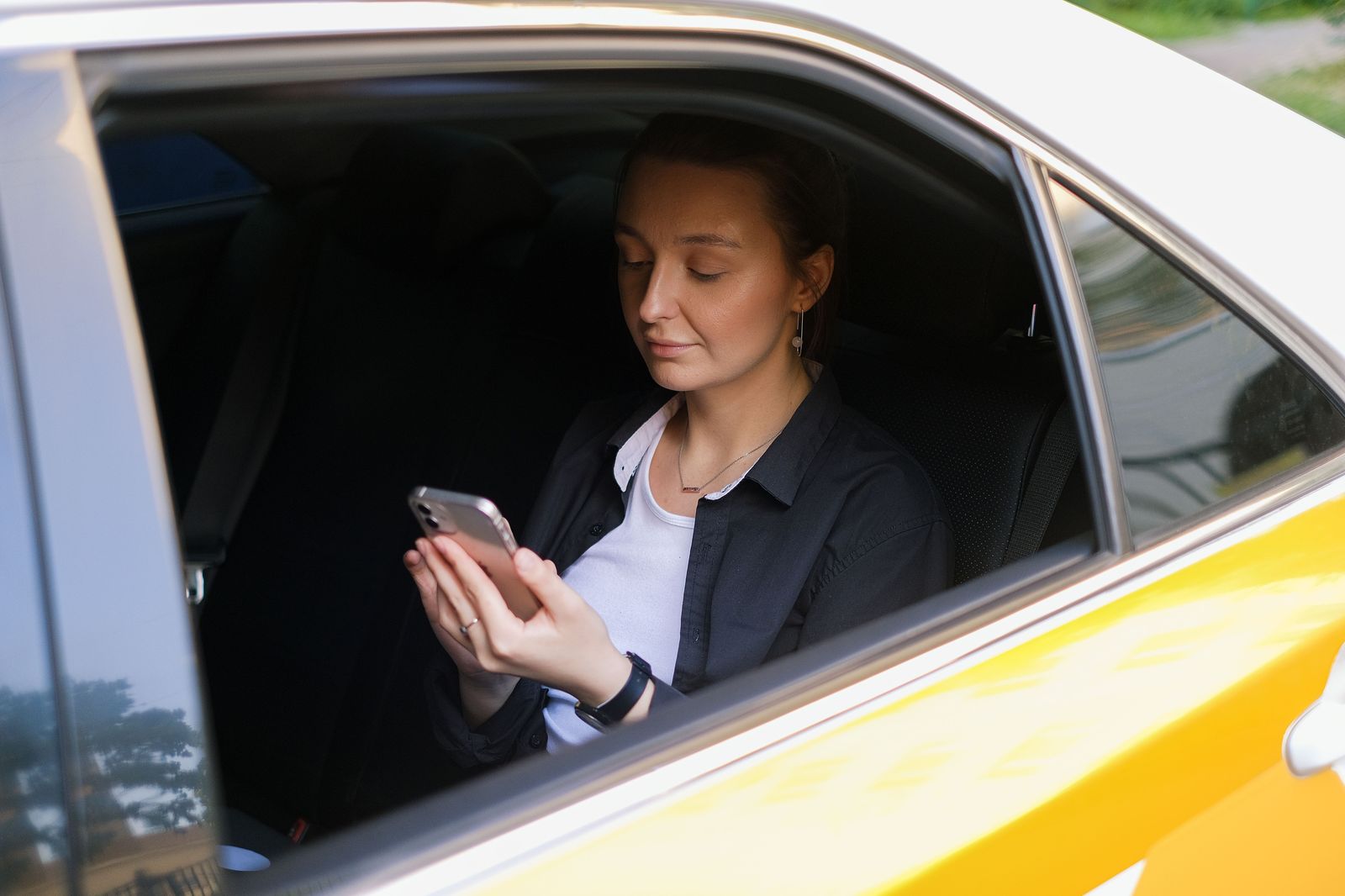 A traveller checking a ride-hailing app on a phone at the kerb