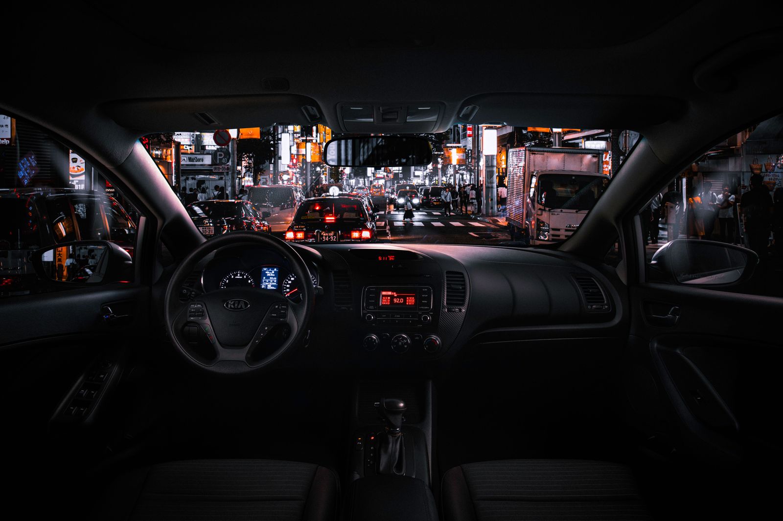 A black sedan waiting on a city street at night