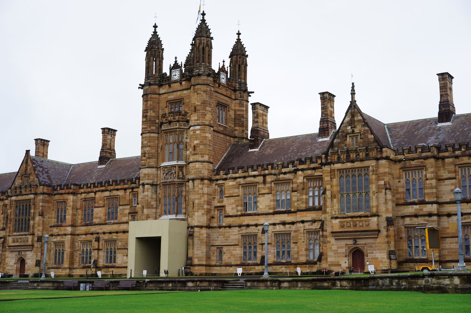 An old stone university building framed by trees on convocation day