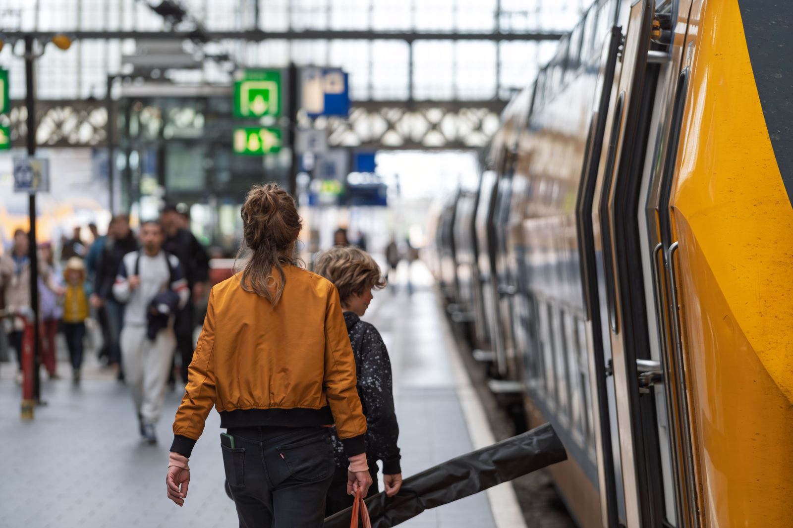 Travellers with luggage walking along a train platform towards the station concourse