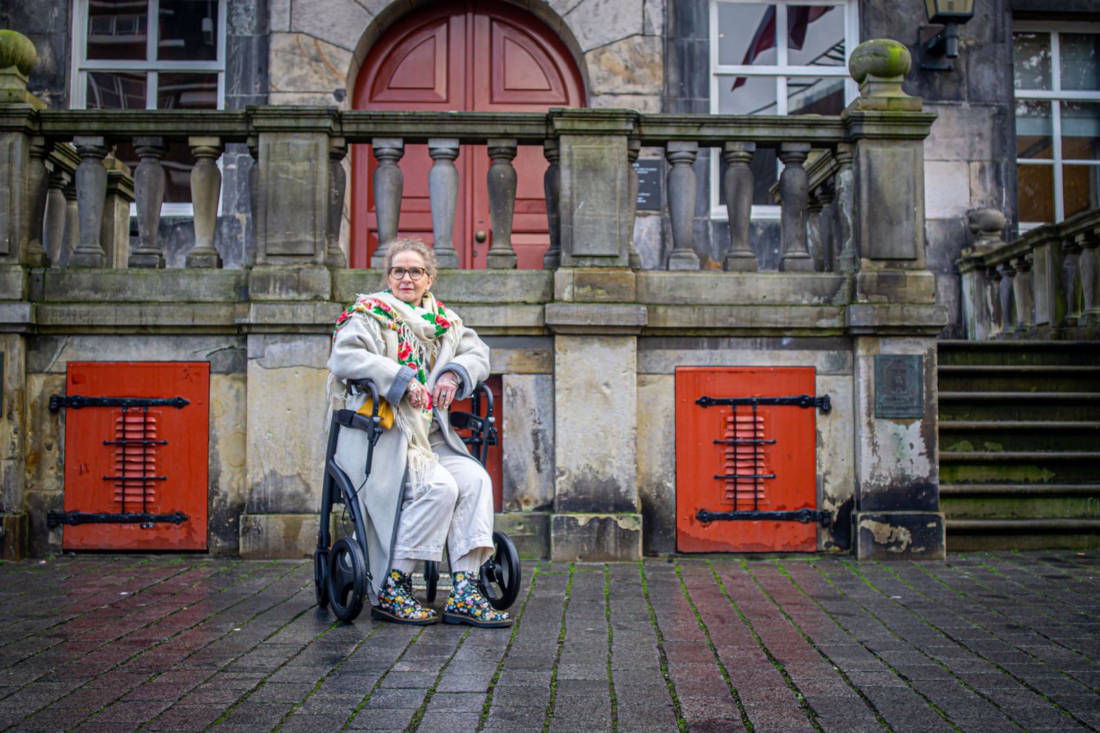 A chauffeur holding the door as a passenger with a walker gets into a car