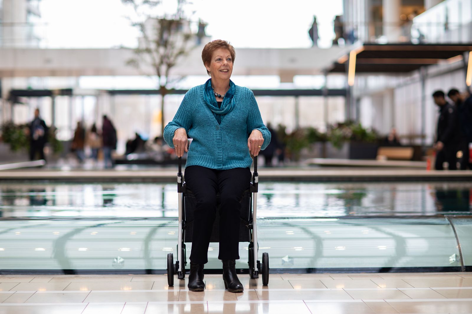 Elderly traveller being helped through an airport arrivals hall