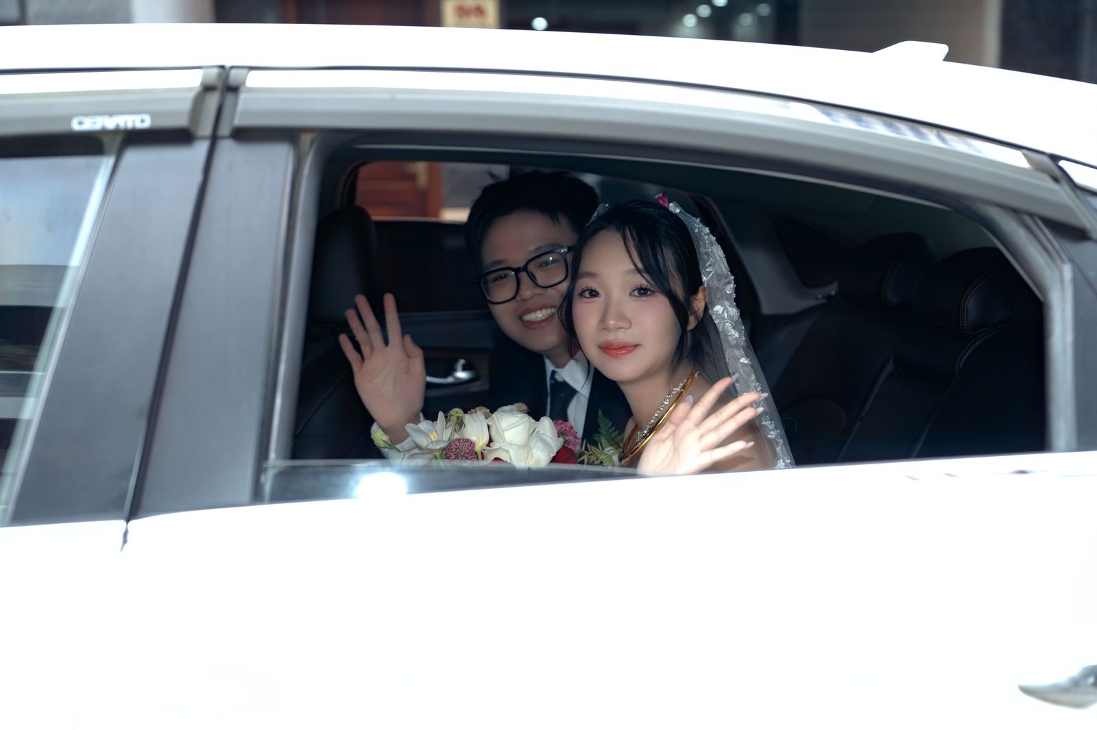 Parents waving goodbye as a car leaves the driveway