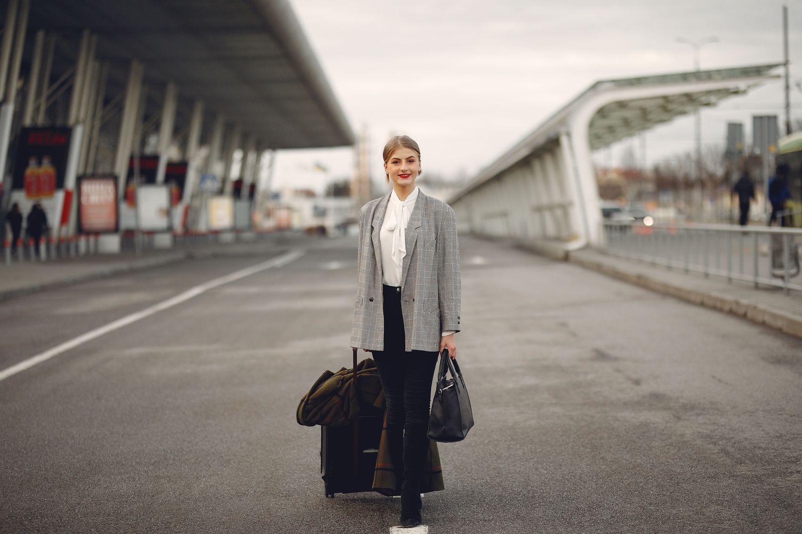 Family with suitcases waiting at the curb outside an airport terminal